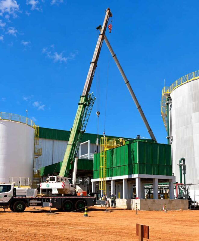 Instalação da torre de resfriamento industrial da Brasbio com guindastes e estrutura metálica de suporte.